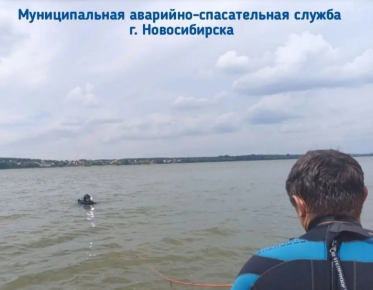Спасательный катер и водолазы аварийно-спасательной службы в гидрокостюмах работают на водной глади реки Обь