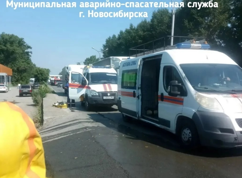 Специалисты аварийно-спасательной службы в защитных костюмах обрабатывают место разлива химического вещества на автомобильной трассе.Заголовок: Работа экстренных служб по ликвидации химического загрязнения в Новосибирске.